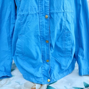 May include: A light blue jacket with a button closure and two pockets. The jacket has a drawstring at the waist.