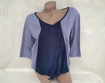 Puede incluir: Una camisa de manga larga a rayas azules y blancas con un panel azul marino y un detalle de botones.