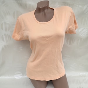 May include: A peach-colored short-sleeved t-shirt with a round neckline.