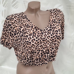 May include: A brown and black leopard print cropped top with a V-neck.