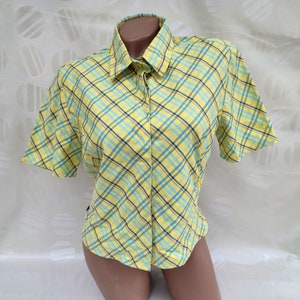Puede incluir: Una camisa de manga corta a cuadros amarillos y azules con botones.