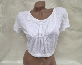 May include: White short-sleeved shirt with a gathered detail and button closure at the neckline. The shirt is cropped and has a relaxed fit.