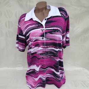 Może przedstawiać: Koszulka z krótkim rękawem w paski w kolorze różowym, czarnym i białym z białym kołnierzykiem i zapięciem na guziki.