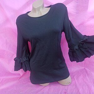 May include: Black long-sleeved shirt with ruffled sleeves.