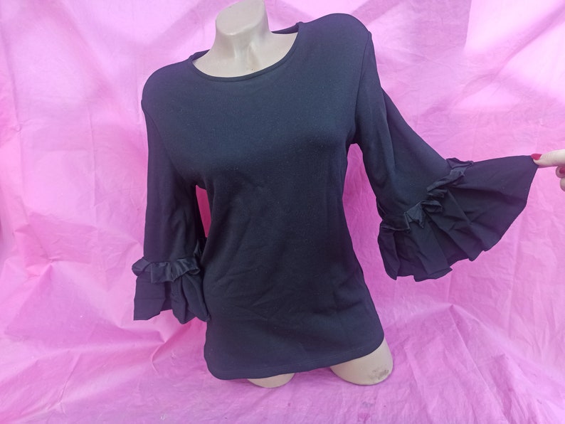 May include: Black long-sleeved shirt with ruffled sleeves.