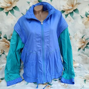 Peut inclure: Une veste coupe-vent bleu et turquoise avec une fermeture éclair et un cordon de serrage à la taille.
