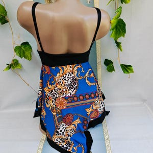 Puede incluir: Un top negro con tirantes finos y una falda azul estampada. La falda presenta un dise&ntilde;o dorado y blanco con detalles de estampado de leopardo. La prenda se exhibe en un maniqu&iacute;.