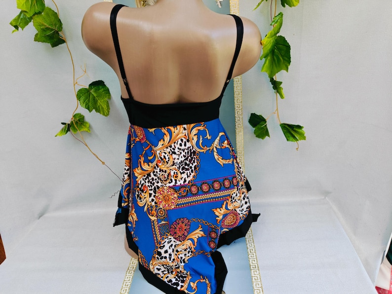 Puede incluir: Un top negro con tirantes finos y una falda azul estampada. La falda presenta un dise&ntilde;o dorado y blanco con detalles de estampado de leopardo. La prenda se exhibe en un maniqu&iacute;.