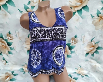 Puede incluir: Un top azul y blanco sin mangas con cuello redondo. El patrón presenta un diseño repetitivo de círculos y líneas.