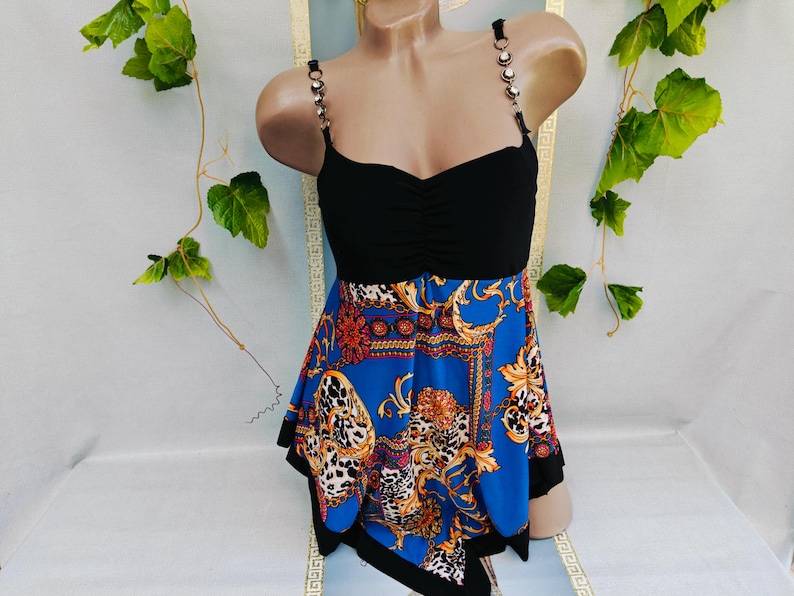 Puede incluir: Top negro con escote coraz&oacute;n y tirantes de cadena. La parte inferior es de tela azul estampada con detalles dorados y rojos. El dise&ntilde;o incluye un estampado de leopardo y detalles ornamentados. La parte superior se muestra en un maniqu&iacute;.