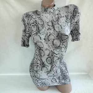 Può includere: Un abito a maniche corte con collo alto e stampa a pelle di serpente in bianco e nero.