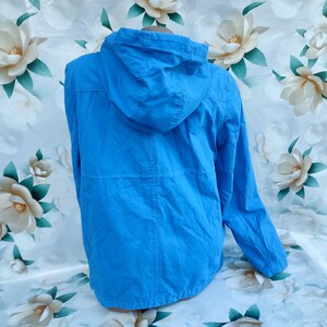 May include: A bright blue hooded jacket with a zipper closure. The jacket is made of a lightweight fabric and has a relaxed fit.