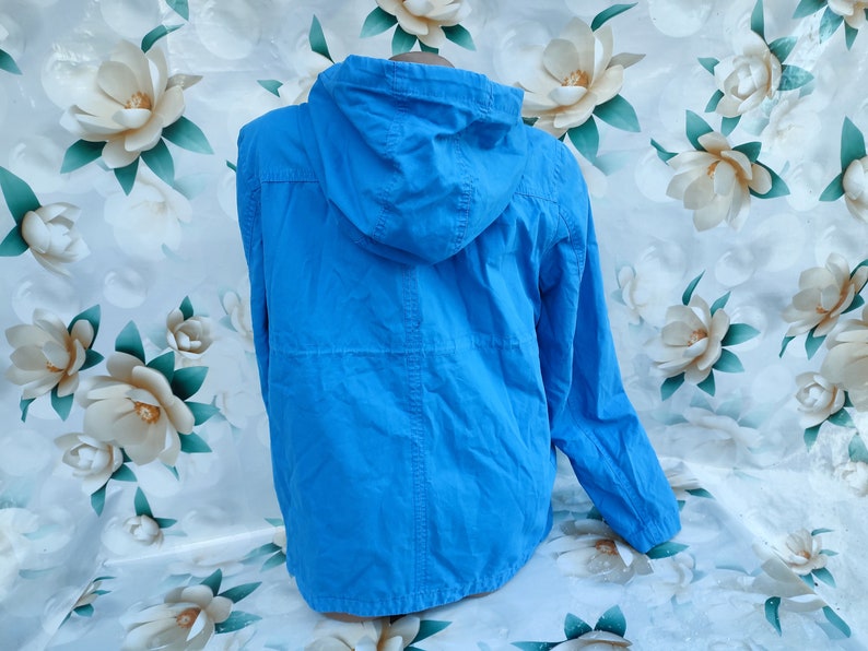 May include: A bright blue hooded jacket with a zipper closure. The jacket is made of a lightweight fabric and has a relaxed fit.