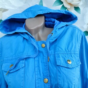 May include: A light blue hooded jacket with gold buttons and a drawstring closure.