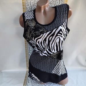 Pode incluir: Top sem mangas preto e branco com um design de patchwork único. Apresenta uma estampa de zebra, bolinhas e bordados florais. A gola e as cavas são acabadas em preto.