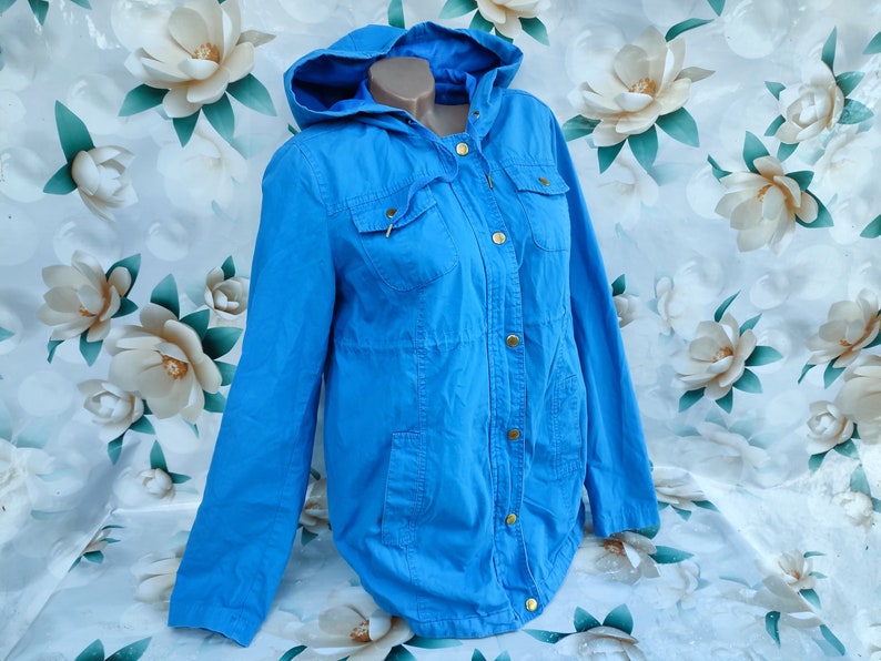 May include: A light blue hooded jacket with gold buttons and pockets.