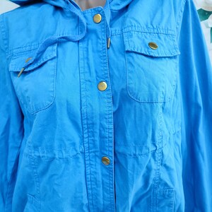 May include: A bright blue hooded jacket with gold buttons and a flap pocket on the front.