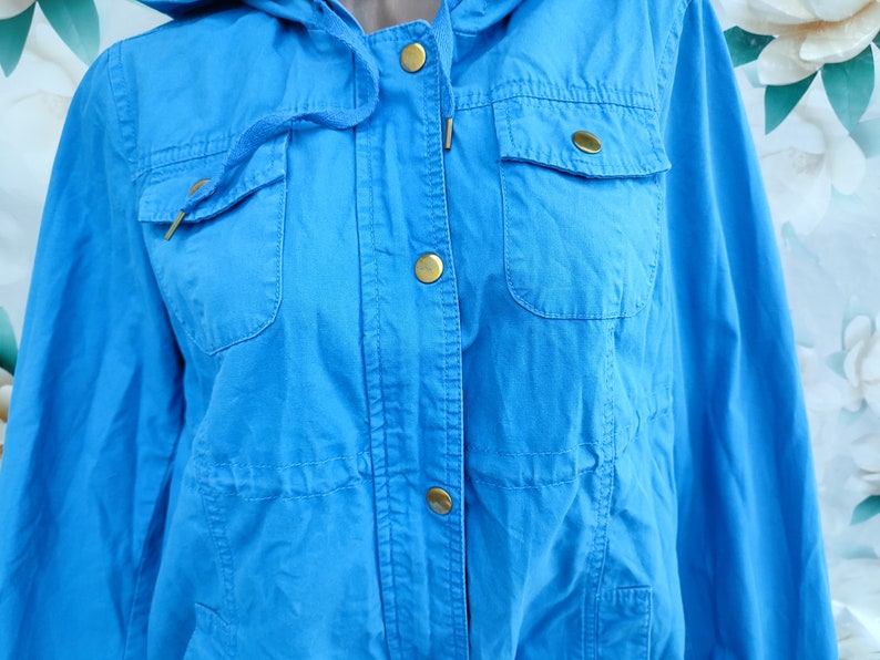 May include: A bright blue hooded jacket with gold buttons and a flap pocket on the front.