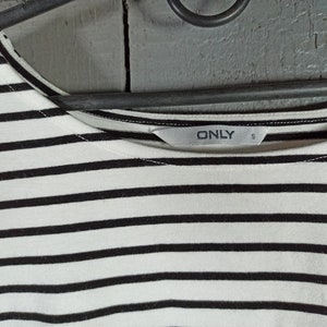 May include: A white and black striped shirt with a black "ONLY" label on the front. The label also has a size "S" printed on it.