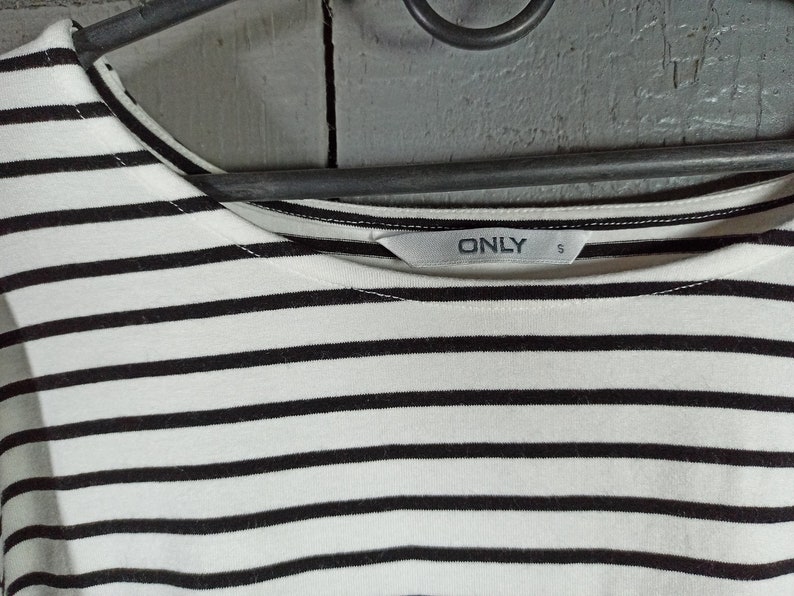 May include: A white and black striped shirt with a black "ONLY" label on the front. The label also has a size "S" printed on it.