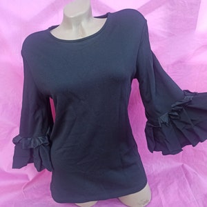 May include: Black long-sleeved shirt with ruffled bell sleeves. The shirt has a round neckline and is made of a soft, stretchy fabric.