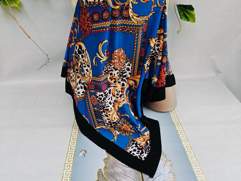 Puede incluir: Un pa&ntilde;uelo azul con borde negro, con un dise&ntilde;o barroco con detalles dorados, rojos y blancos. El pa&ntilde;uelo tiene un estampado de leopardo y un dise&ntilde;o de cadena.