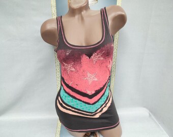 May include: A dark gray tank dress with a heart-shaped design in shades of pink and burgundy, featuring white stars. The dress has a scoop neckline and a striped pattern in teal and peach at the bottom. The dress is displayed on a mannequin.
