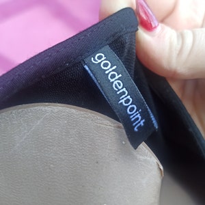 May include: Black clothing label with the text "goldenpoint" in white lettering.