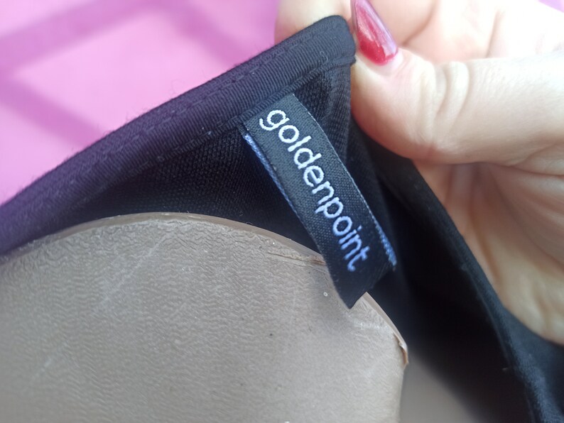 May include: Black clothing label with the text "goldenpoint" in white lettering.