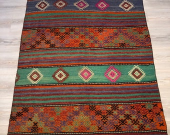 May include: A traditional handwoven rug with a colorful geometric pattern in shades of blue, green, orange, and brown. The rug has a fringe border and is made of wool.