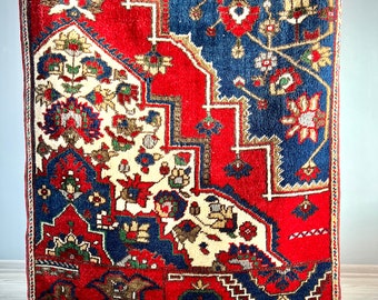 May include: A vintage rug with a red, blue, and white geometric pattern. The rug has a fringe border and is made of wool.