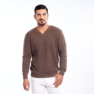 Puede incluir: Un suéter marrón de cuello en V con mangas largas y un hombre con jeans blancos y zapatillas negras.