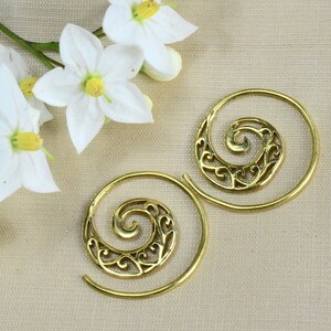 Könnte beinhalten: Ein Paar goldfarbene Spiral-Creolen mit einem filigranen Design. Die Ohrringe sind aus Messing und haben eine runde Form.