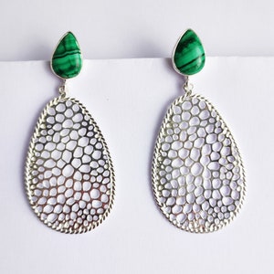 May include: A pair of silver dangle earrings with a green malachite stone at the top of each earring. The earrings have a delicate, openwork design.