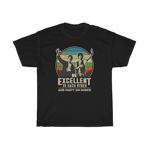以下が含まれることがあります： 「Be Excellent to Each Other and Party On Dudes!」というテキストが書かれた円の中に、2人の男性が描かれたヴィンテージスタイルのグラフィックがプリントされた黒いTシャツ