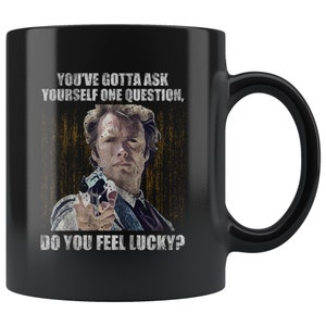 May include: Black ceramic mug with a graphic of Clint Eastwood from the movie "Dirty Harry". The graphic features Eastwood holding a gun and the text "You've gotta ask yourself one question, Do you feel lucky?"