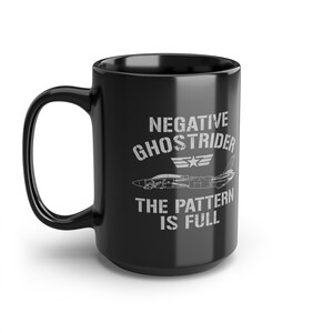 Puede incluir: Taza de café de cerámica negra con un gráfico blanco de un avión de combate y el texto "Negative Ghostrider The Pattern Is Full".