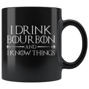 May include: Black ceramic coffee mug with white text that reads "I drink bourbon and I know things".