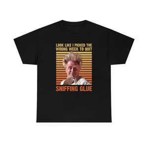 May include: Black t-shirt with a retro-style graphic of a man with messy hair, holding a tube of glue. The text reads "Look like I picked the wrong week to quit sniffing glue."