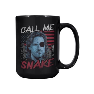 Può includere: Tazza in ceramica nera con una grafica di un uomo con una benda sull'occhio e il testo "Call Me Snake" in lettere rosse e bianche. La grafica è su uno sfondo di bandiera americana rosso, bianco e blu.