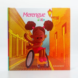 May include: A children's book cover with a colorful illustration of a girl in a wheelchair smiling and dancing in a street with yellow buildings. The title of the book is "Merengue Aiko" and the author is "Brenda Ramirez".