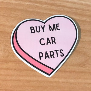May include: Pink heart-shaped sticker with the text "BUY ME CAR PARTS" in black lettering.