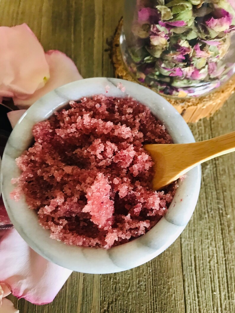 May include: A close-up of a white bowl filled with pink sugar scrub. The scrub is made with rose petals and is perfect for exfoliating the skin.