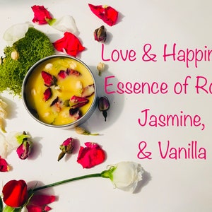Op de afbeelding: Een witte kaars met gedroogde rozenblaadjes en andere botanische elementen in een zilveren blik. De kaars is omringd door rozenblaadjes en andere bloemen. De tekst "Love & Happiness Essence of Rose, Jasmine, & Vanilla" is in roze op een witte achtergrond geschreven.