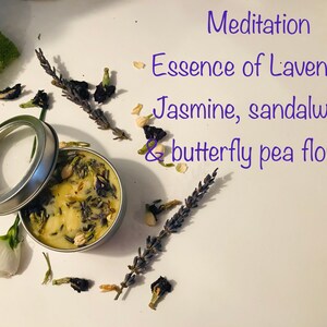 Op de afbeelding: Een klein blikje met een kaars en een doorzichtig deksel. De kaars is wit met lavendel, jasmijn en sandelhoutbloemen. De tekst op het etiket luidt "Meditation Essence of Lavender, Jasmine, sandalwood & butterfly pea flowers".