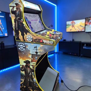 Può includere: Un cabinato arcade personalizzato a tema pirata. Il mobile presenta opere d'arte di pirati, navi e teschi. Il pannello di controllo ha joystick e pulsanti. Il testo "WARNING PIRATES" è visibile.