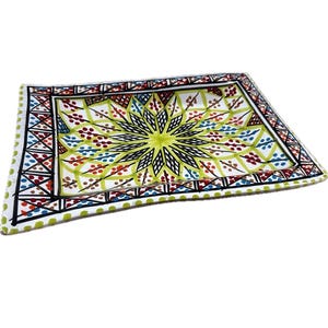 May include: Rectangular ceramic tray with a vibrant floral design. The centre features a yellow starburst pattern, surrounded by a border of red, blue, and green accents. The tray's edges are outlined in black.