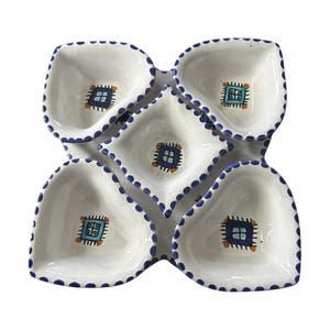 Può includere: Piatto da portata in ceramica bianca con cinque sezioni collegate. Ogni sezione ha un bordo a pois blu e un design quadrato ricamato al centro. Il design presenta colori blu, arancione e bianco.
