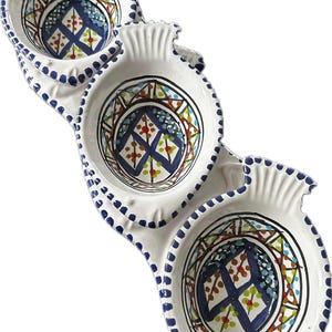 Könnte beinhalten: Weißes Keramik-Serviertablett mit drei verbundenen Schalen. Jede Schale hat ein farbenfrohes geometrisches Design in Blau, Grün, Rot und Gelb. Die Ränder sind mit blauen Punkten und gewellten Kanten verziert.