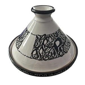 Könnte beinhalten: Weißer Keramik-Tagine-Topf mit konischem Deckel und breitem, flachem Boden. Der Topf weist schwarze, stilisierte Kalligraphie-Designs auf dem Deckel und dem Bodenrand auf. Der Rand und die Oberseite des Deckels sind mit einem schwarzen Band akzentuiert.